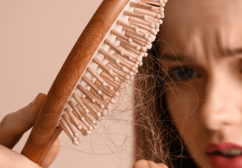 femme qui a sa brosse remplie de cheveux suite à une chute printanière