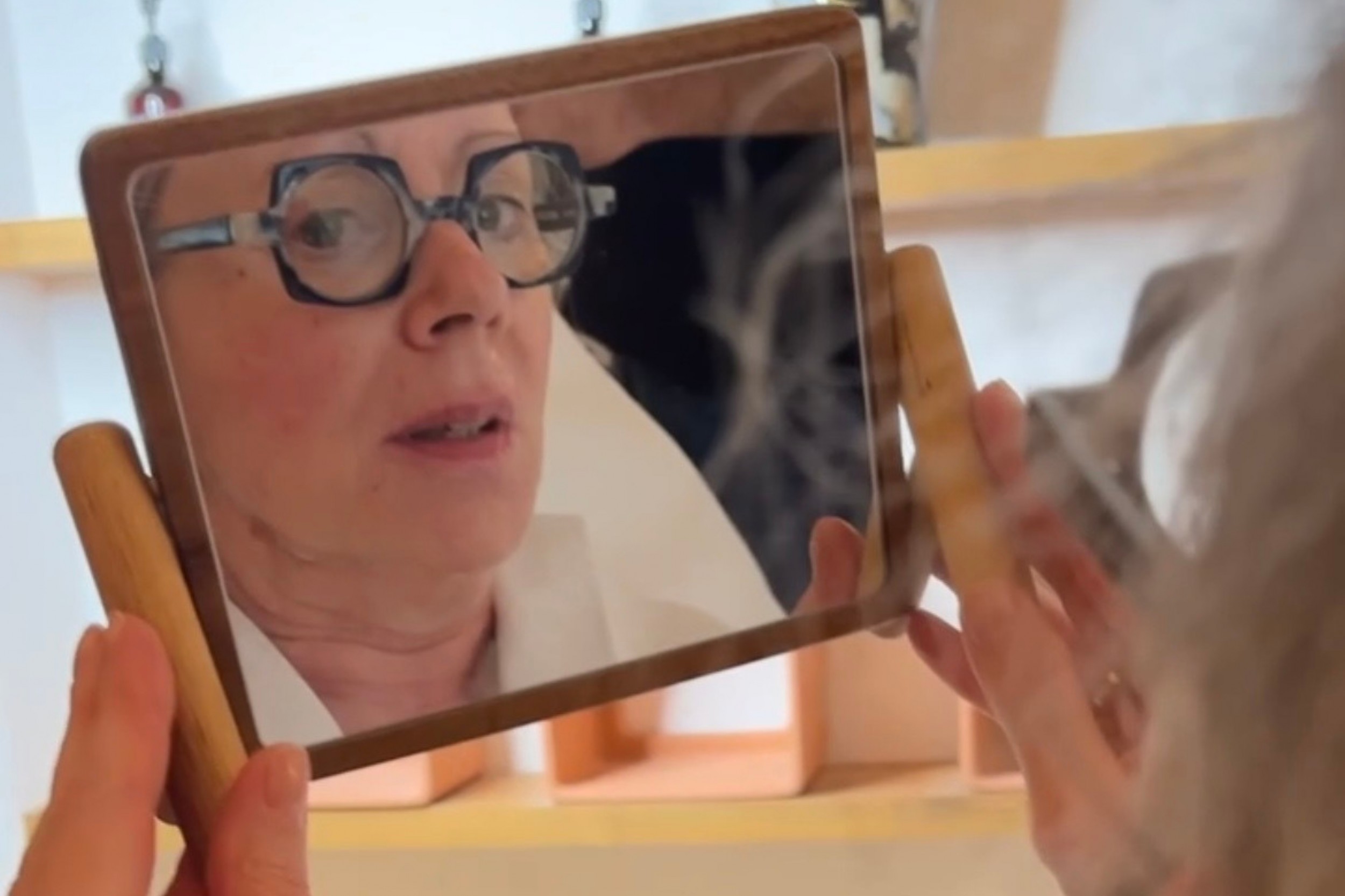 Une femme qui observe dans un miroir les résultats du soin anti-âge de chez aesthé