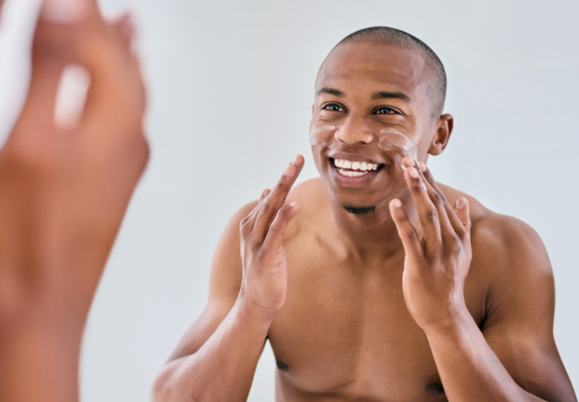 Un homme qui se met de la crème à base d'acide hyaluronique et un sérum à base de Vitamine C